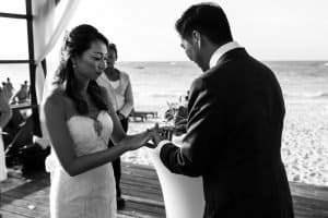 Groom puts a ring on bride's finger standing on the beach